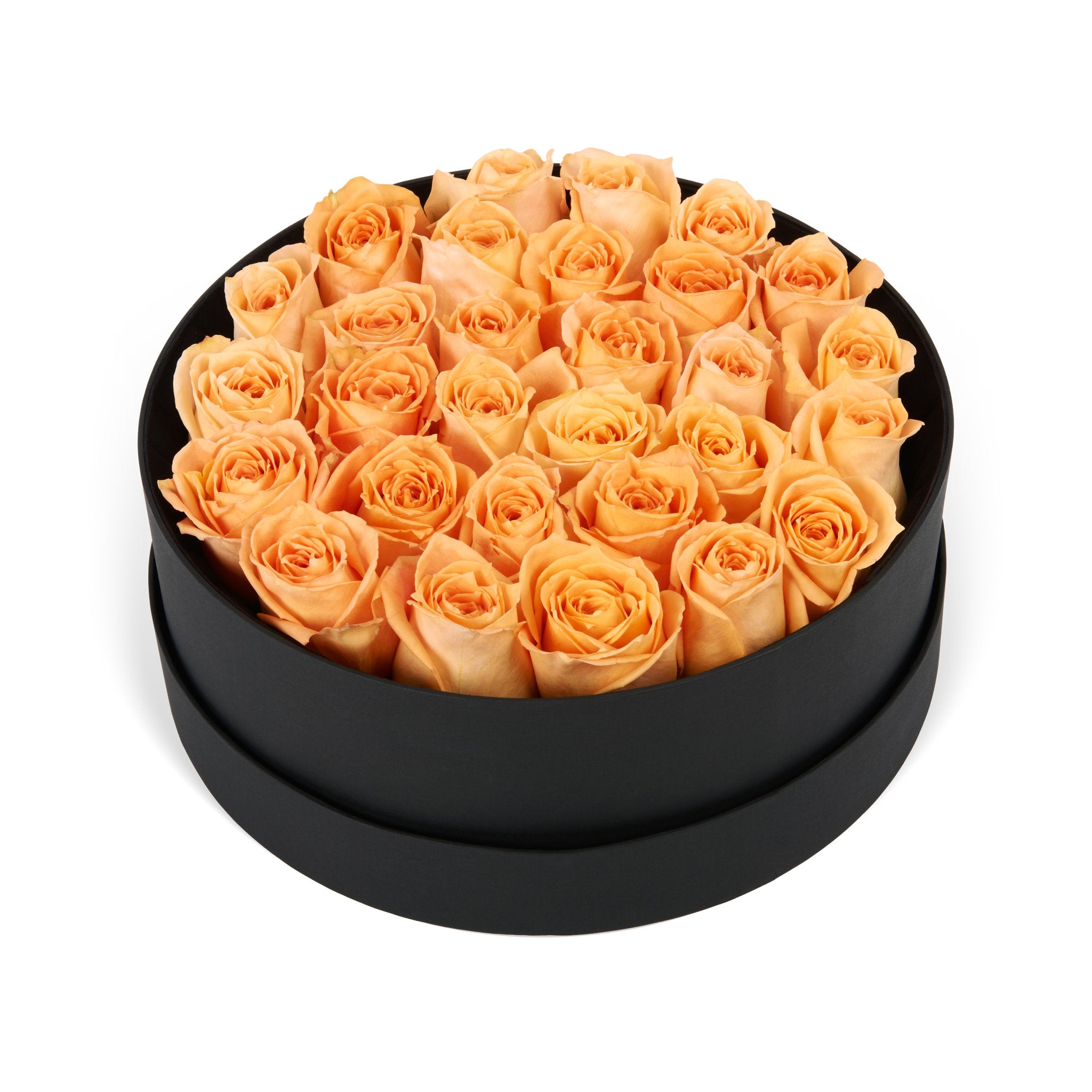 Black round box filled with peach roses on a white background