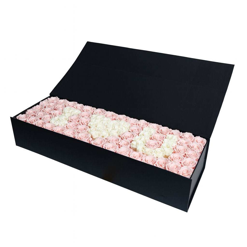 Black box filled with pink and white roses on a white background