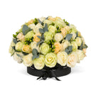 Floral arrangement in a black box with greenery on a white background