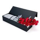 Black gift box with red roses and gray fabric inside on a white background