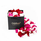 Black 'Only Roses' bag filled with red, pink, and white rose petals on a white background