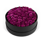 Black round box filled with purple roses on a white background