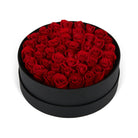 Black round box filled with red roses on a white background