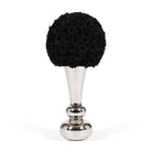 Decorative object with black rose ball on a silver stand against a white background
