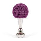 Decorative object with purple spherical rose arrangement on a silver stand against a white background