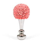 Decorative item with coral-colored rose ball on a silver stand against a white background