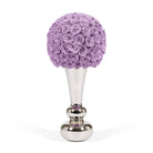 Decorative object with purple rose ball on a silver stand against a white background