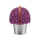 Silver bucket filled with purple roses on a white background