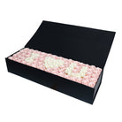 Black box filled with pink and white roses on a white background