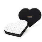 Heart-shaped box filled with white roses and branded lid on a white background