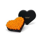 Heart-shaped box of orange roses with a black heart-shaped container on a white background