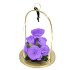Purple roses in a glass dome with gold base on a white background