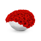 White spherical vase filled with red roses on a white background