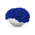 White spherical vase filled with blue roses on a white background