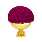 Spherical arrangement of purple roses on a gold pedestal against a white background