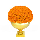 Spherical arrangement of orange roses on a gold pedestal against a white background