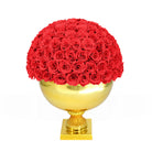 Red roses in a gold spherical vase on a white background