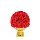 Red rose ball on a gold pedestal against a white background