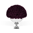 Bouquet of dark purple roses on a white pedestal against a white background