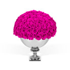 Spherical arrangement of pink roses in a silver vase on a white background