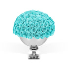 Bouquet of turquoise roses in a silver vase on a white background