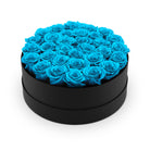 Black round box filled with blue roses on a white background