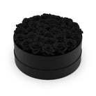 Black round box filled with black roses on a white background