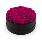 Black round box filled with pink roses on a white background