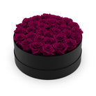 Black round box filled with purple roses on a white background