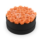 Black round box filled with orange roses on a white background