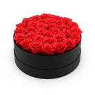Black round box filled with red roses on a white background