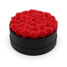 Black round box filled with red roses on a white background