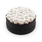 Black round box filled with white roses on a white background