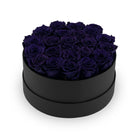 Black round box filled with dark blue roses on a white background