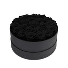 Black round box filled with black roses on a white background