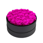 Black round box filled with bright pink roses on a white background