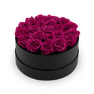 Black round box filled with pink roses on a white background