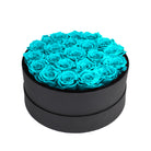Black round box filled with turquoise roses on a white background