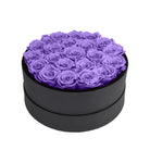 Black round box filled with purple roses on a white background