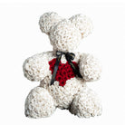 Teddy bear made of white roses with a red heart and black ribbon on a white background