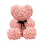 Pink teddy bear made of roses with a black bow on a white background