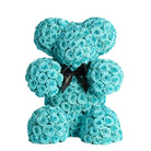 Turquoise rose teddy bear with a black bow on a white background