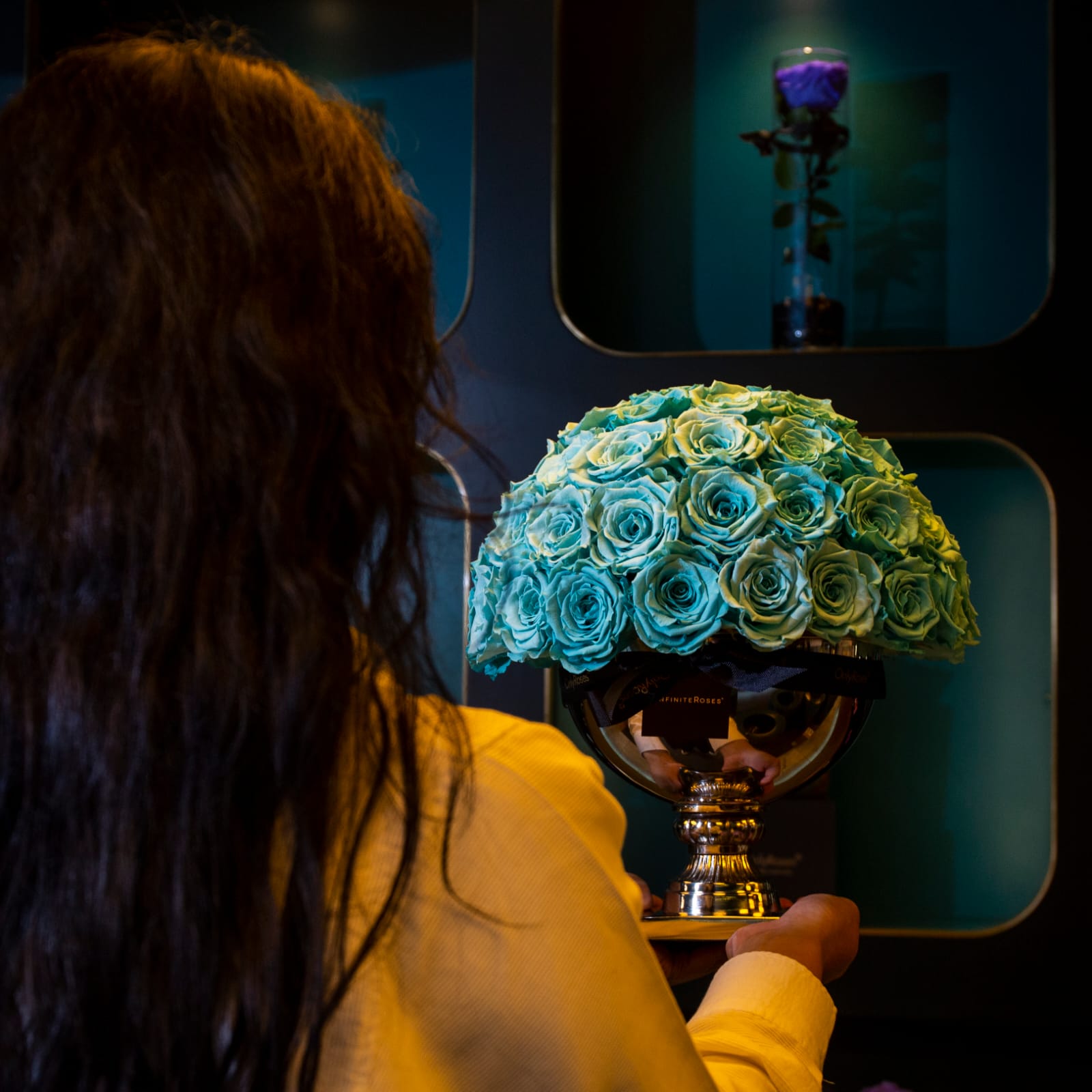 Person holding a bouquet of blue roses in front of a mirror