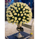 Large bouquet of white roses in a decorative vase on a cart.