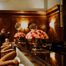 Decorative floral arrangements on a bar counter with wooden paneling in the background. Chamagne Bowls