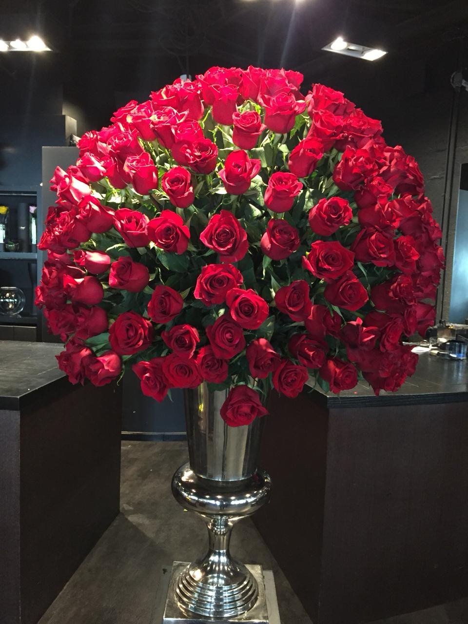 Large bouquet of red roses in a silver vase on a dark background