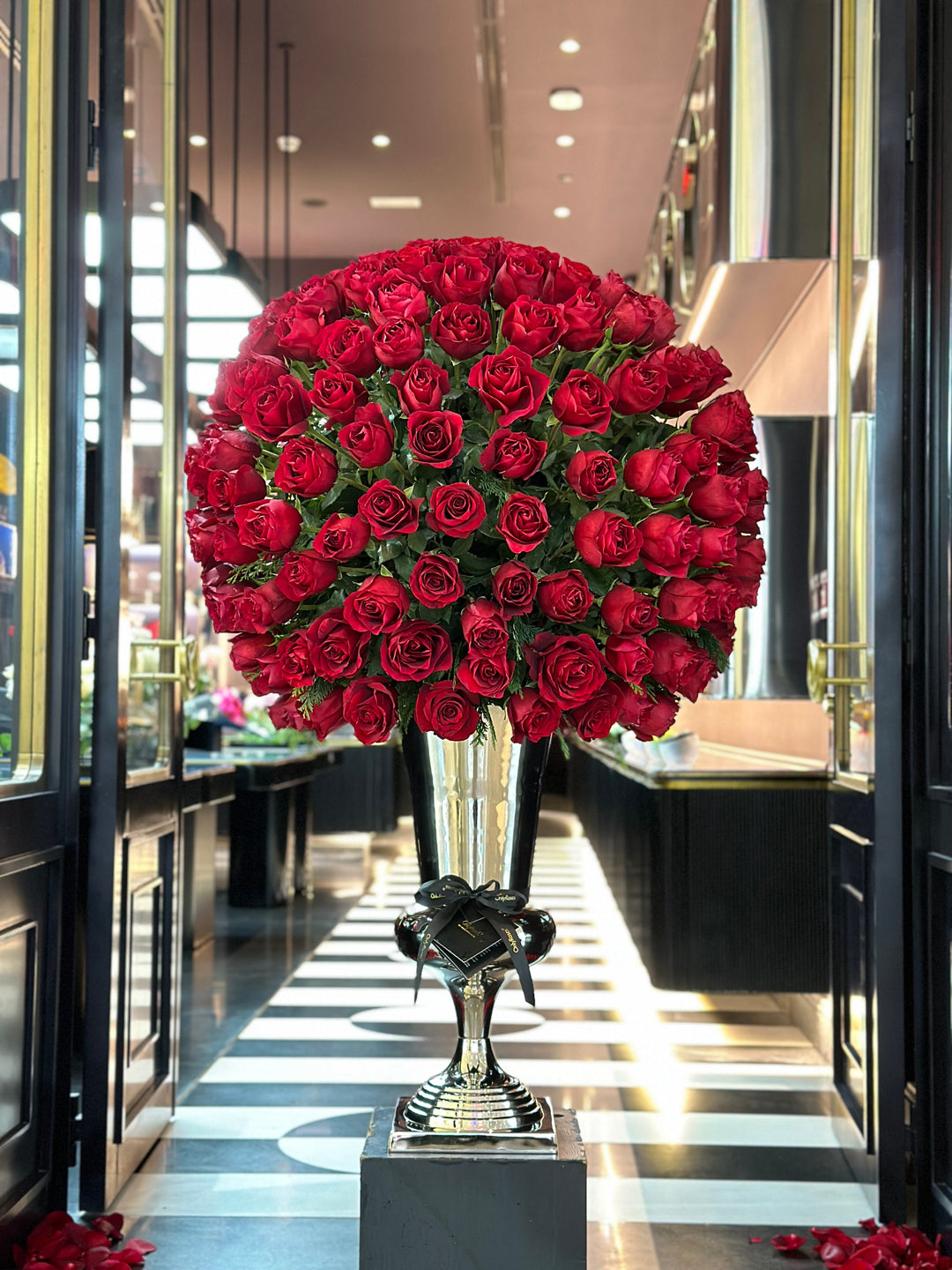 Large bouquet of red roses in a silver vase inside a store.